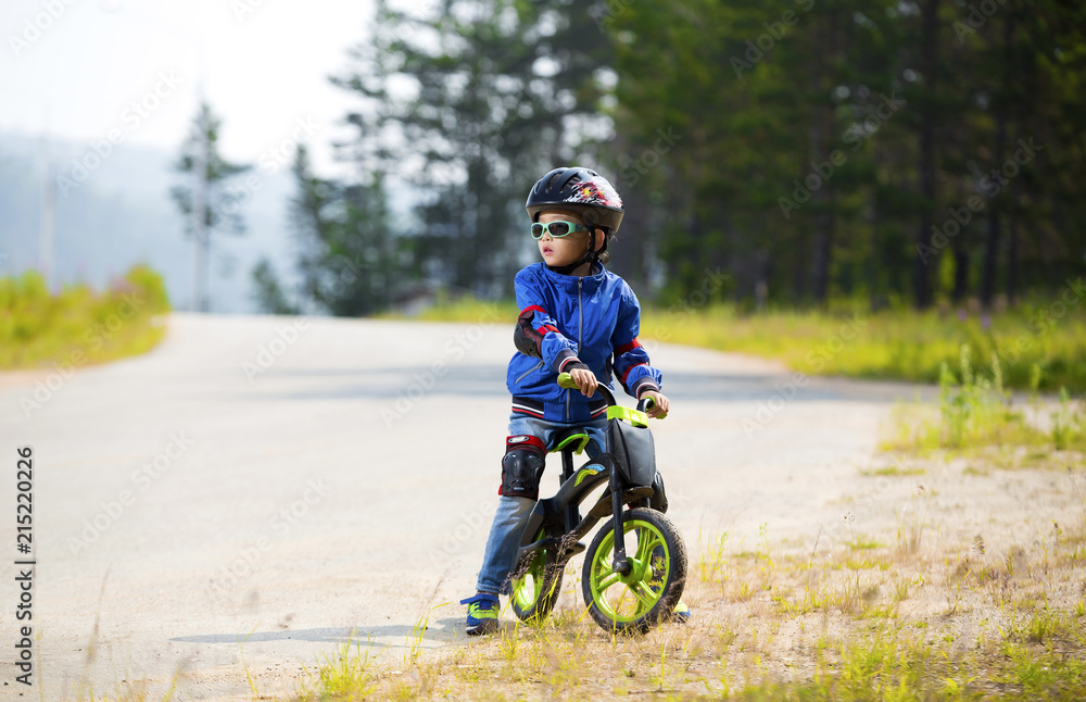 Happy boy having fun riding a bicycle with glasses, helmet, in defense