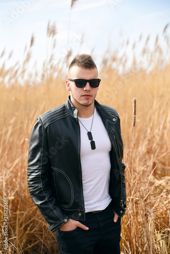 Young man wearing sunglasses and leather jacket in nature