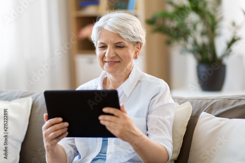 technology, age and people concept - happy senior woman with tablet pc computer at home