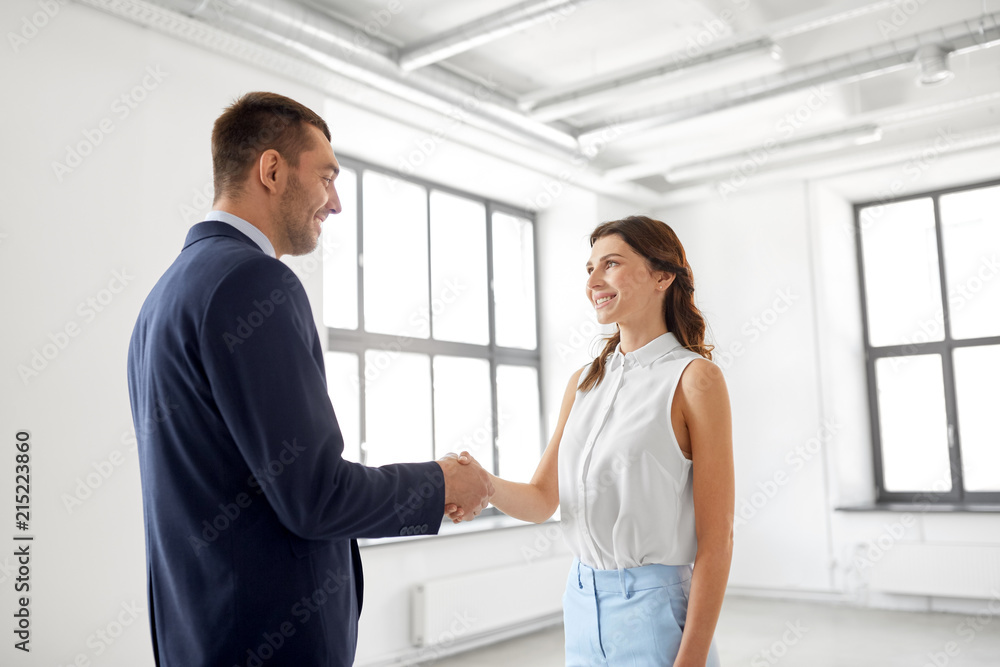 business people, partnership and cooperation concept - happy smiling businesswoman and businessman shaking hands at office