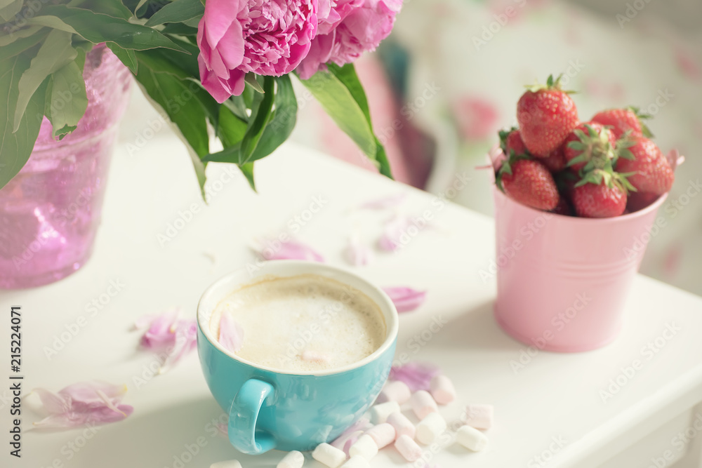 Gentle flowers are pink peonies, coffee with fluffy white milk foam and strawberries. The atmosphere of romance and pleasure.
