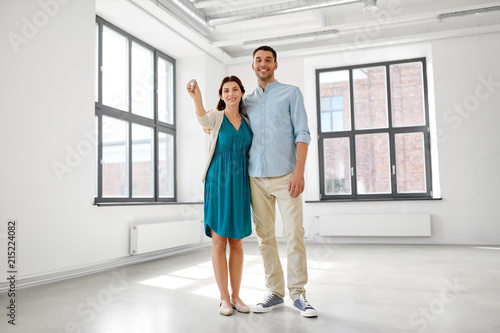 mortgage, people and real estate concept - happy couple with keys at empty room of new home