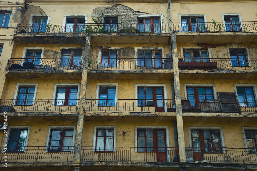 Old collapsing apartment building. The wall of the building, Windows and balconies
