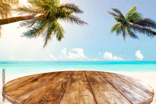Table background of dark brown color and landscape of beach with sea and two palms. 