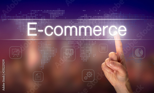 A hand selecting a E-Commerce business concept on a clear screen with a colorful blurred background.