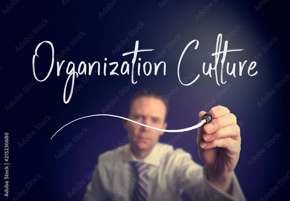 A businessman writing a organisation culture concept with a white pen on a clear screen. A businessman writing a organisation culture concept with a white pen on a clear screen.