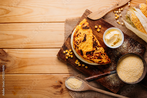 Typical Venezuelan cuisine, Top view of a wooden table with several ingredients for the preparation of Cachapas with cheese, corn, butter, ground corn and white cheese photo