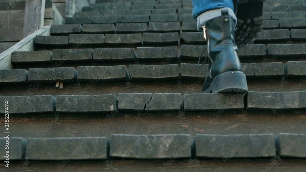 legs woman climb wooden stairs in blue jeans and black boots legs woman climb wooden stairs in blue jeans and black boots