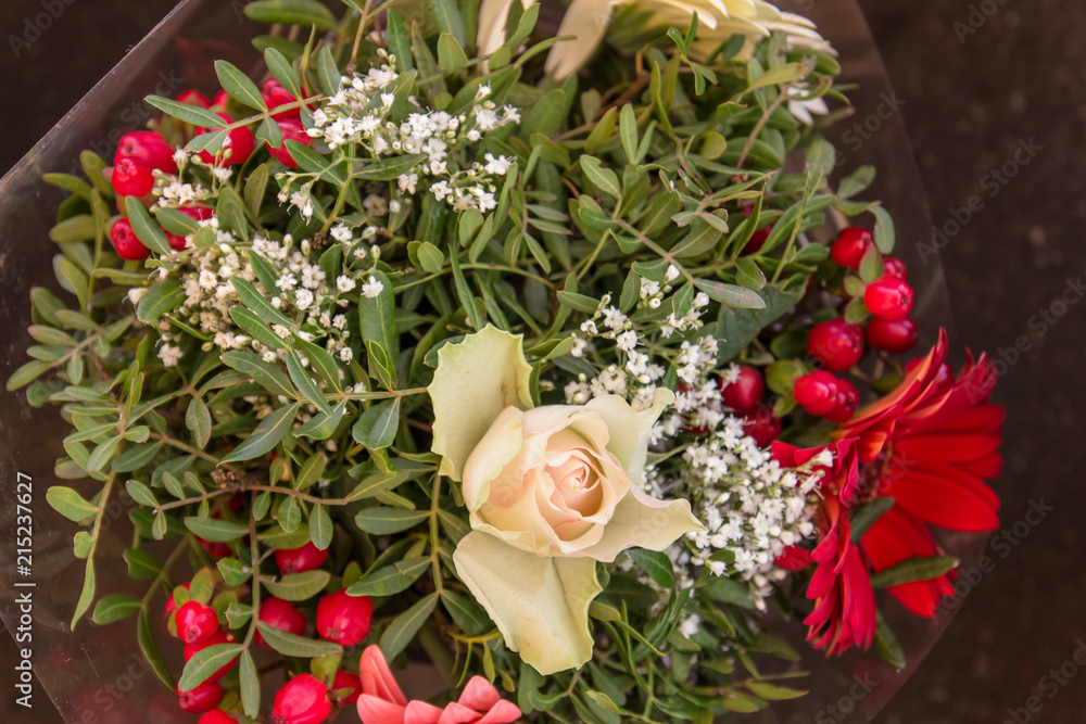 Minimalistic bouquet with greens, red flowers and a white rose in the center Minimalistic bouquet with greens, red flowers and a white rose in the center