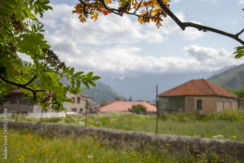 A beautiful mountain landscape, overlooking a village adorned with green grass and blue sky