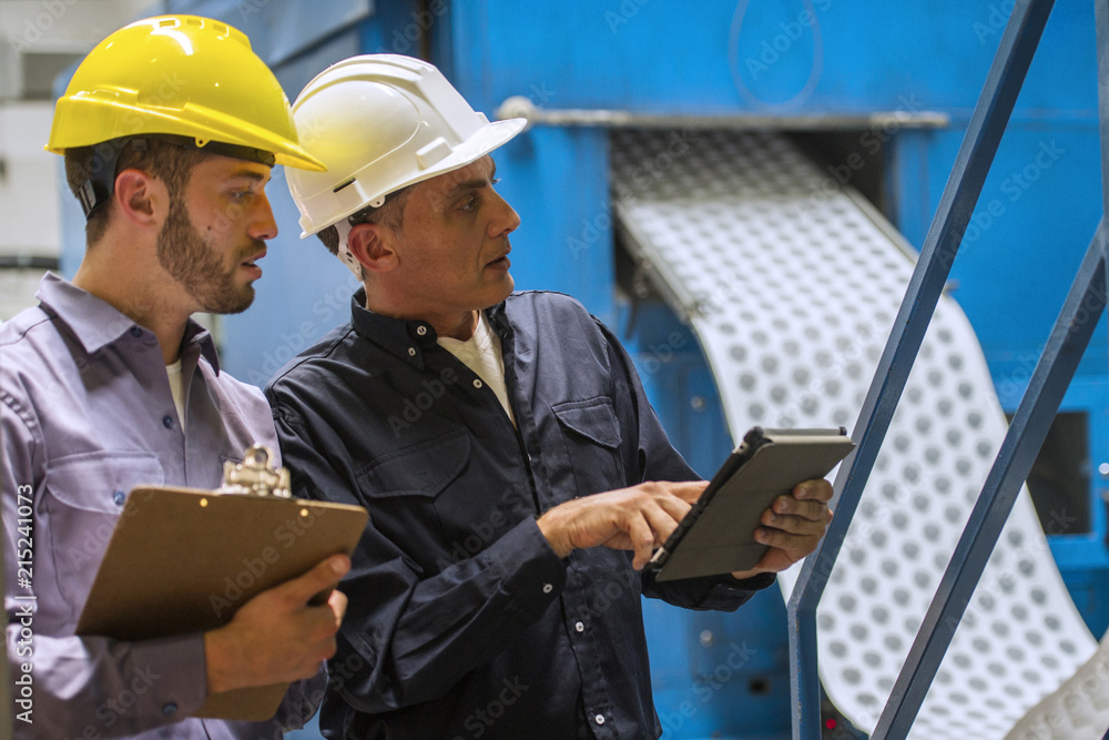 Factory workers discussing with each other in factory Factory workers discussing with each other in factory
