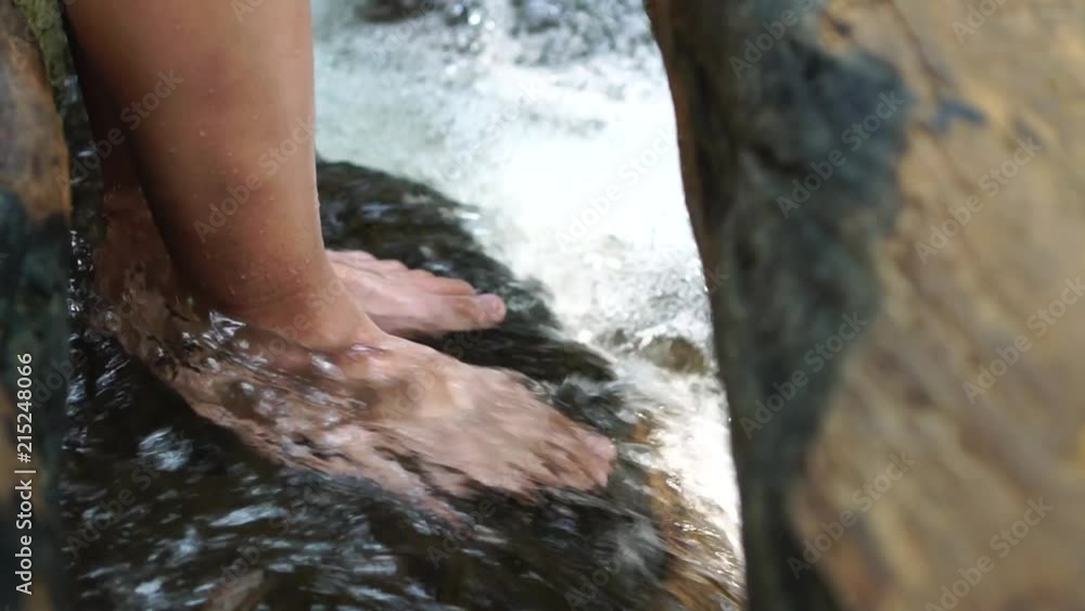Relaxing for life, natural therapy concept : Young man's feet standing on rocks with clear, cold water. Feel comfortable and relax in nature of forest with water flowing on summer day, slow motion Relaxing for life, natural therapy concept : Young man's feet standing on rocks with clear, cold water. Feel comfortable and relax in nature of forest with water flowing on summer day, slow motion