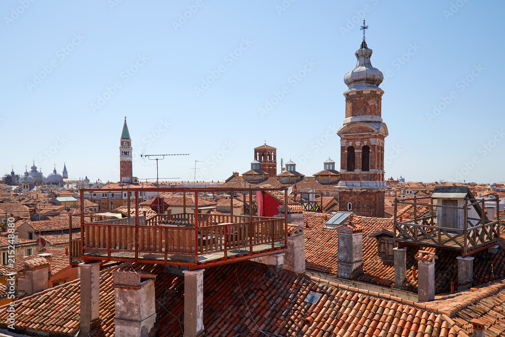 Elevated view of Venice roofs with typical altana balcony and San Marco bell tower in summer, Italy