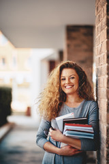 Girl standing against the brick wall and holding book.