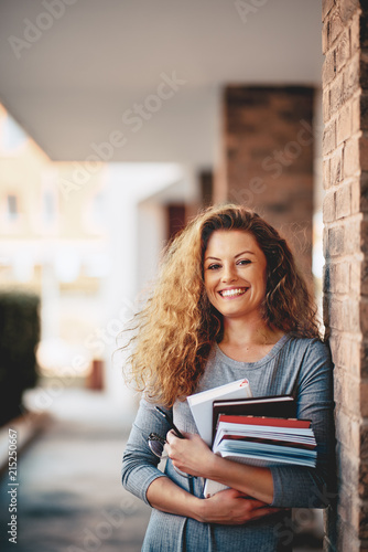 Girl standing against the brick wall and holding book. photo