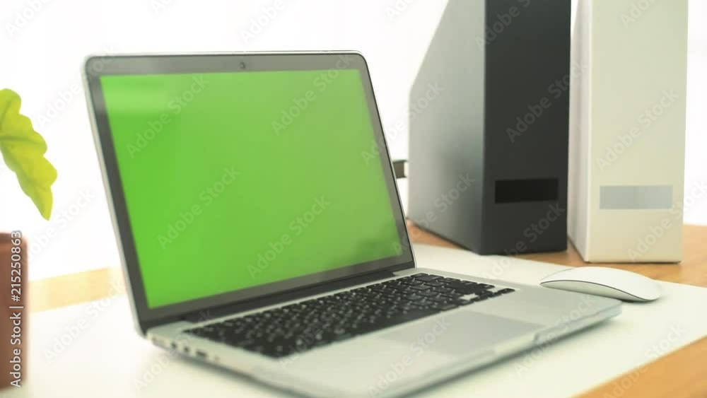 A laptop computer with a key green screen set on work office table. A laptop computer with a key green screen set on work office table.