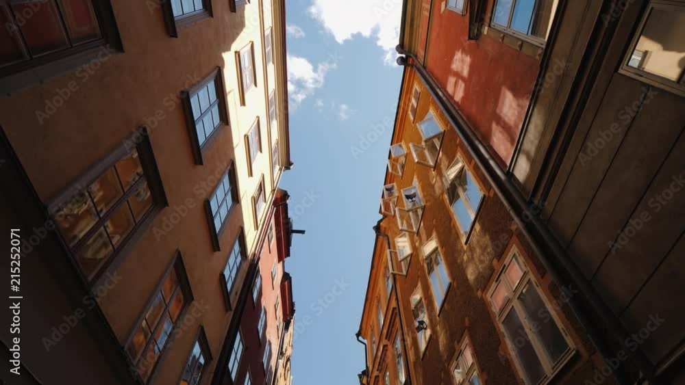 The beautiful narrow street of Stockholm. The open windows reflect the sky and the sun. Architecture of Europe