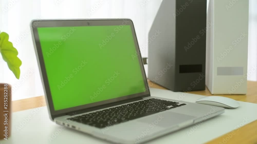 A laptop computer with a key green screen set on work office table. A laptop computer with a key green screen set on work office table.