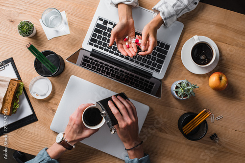 Vászonkép cropped shot of stressed businesspeople with pills and alcohol at workplace