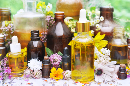 Essential oil bottles on medicinal flowers and herbs background  selective focus