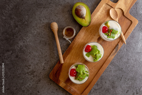 Glass of Cherry and avocado sliced in yogurt on wooden background