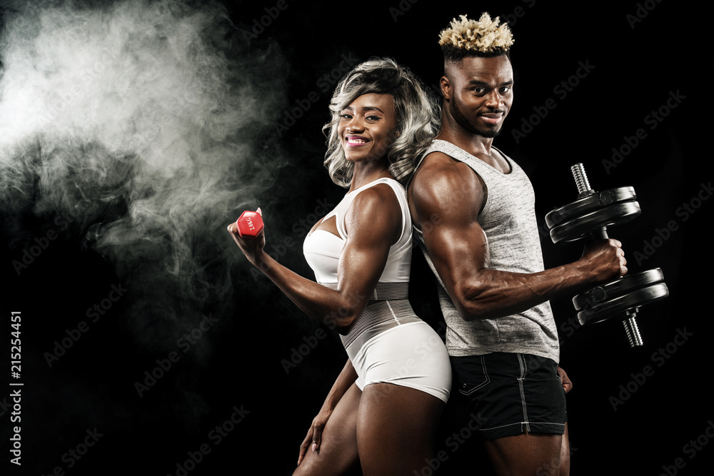 Fitness couple of athletes posing on black background, healthy