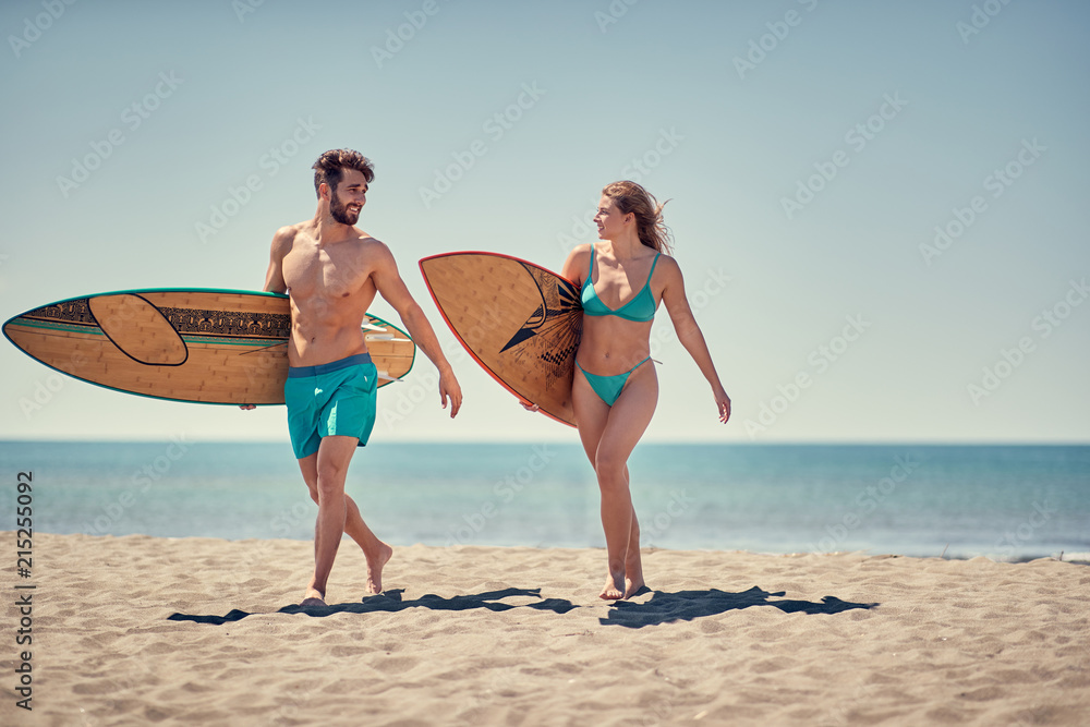Healthy Active Lifestyle. Surfing. man and woman surfers going together to surf at the beach . Healthy Active Lifestyle. Surfing. man and woman surfers going together to surf at the beach .