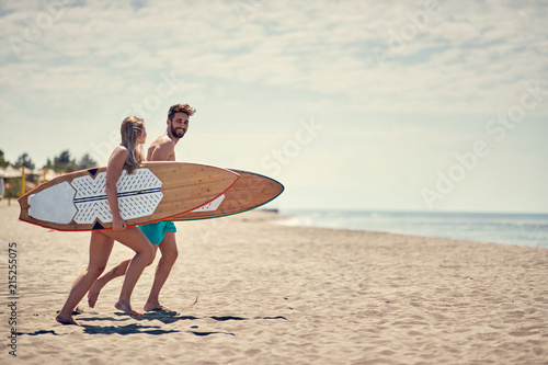 Photography Happy couple surfers going together to surf at the beach .