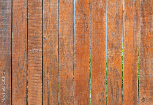 The weathered old gray wooden fence is painted with a bright orange color  close-up