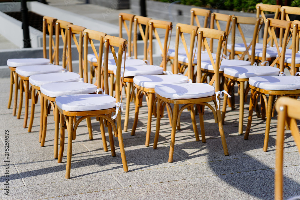 Wooden folding lawn chairs line up in a row with white seat for
