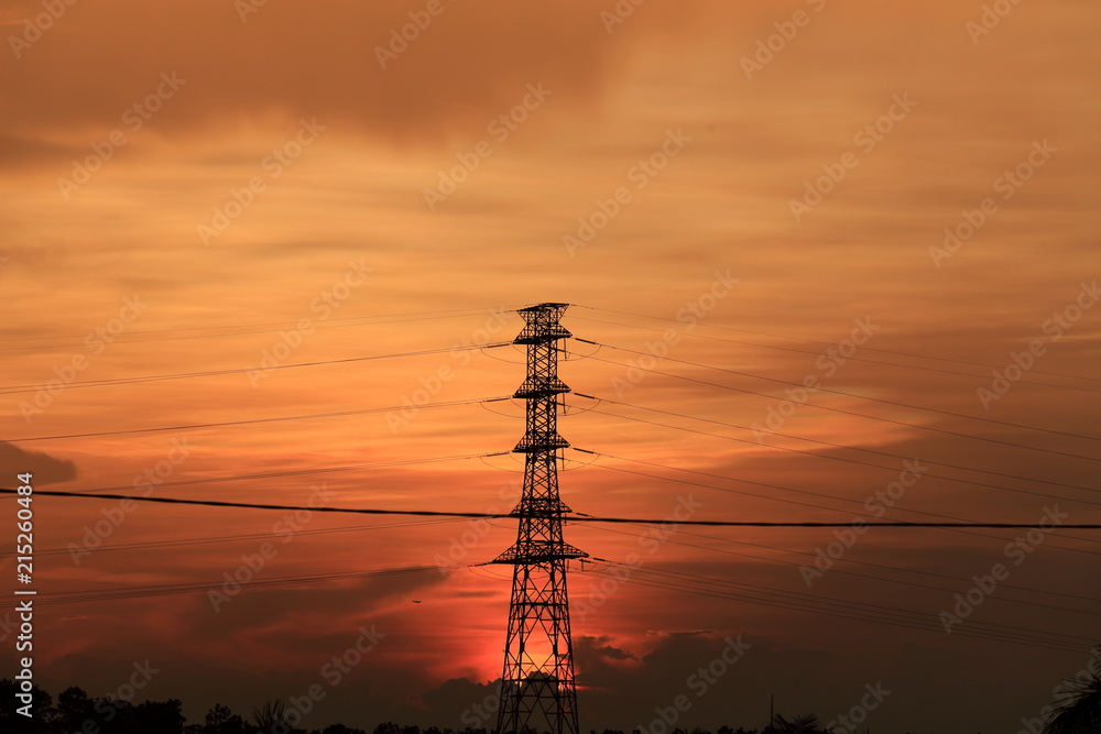 Beautiful sunset with an airplane in the background and the high voltage post at foreground 