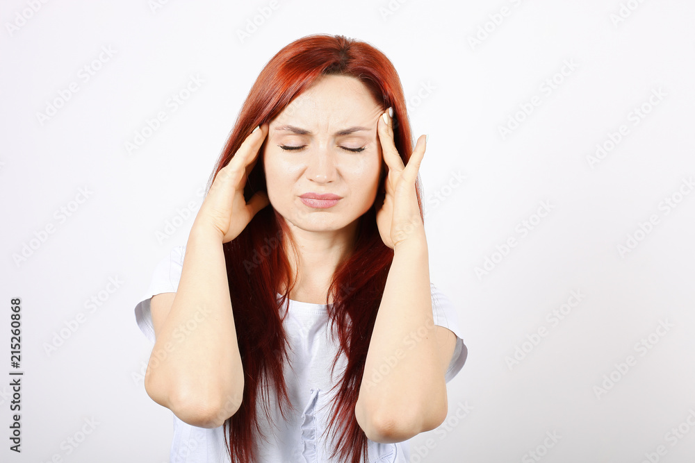 Beautiful redheaded young woman experiencing severe migraine writhing with pain. Pretty female suffering from head ache. Nonverbal behavior, body language. White background, close up, copy space.