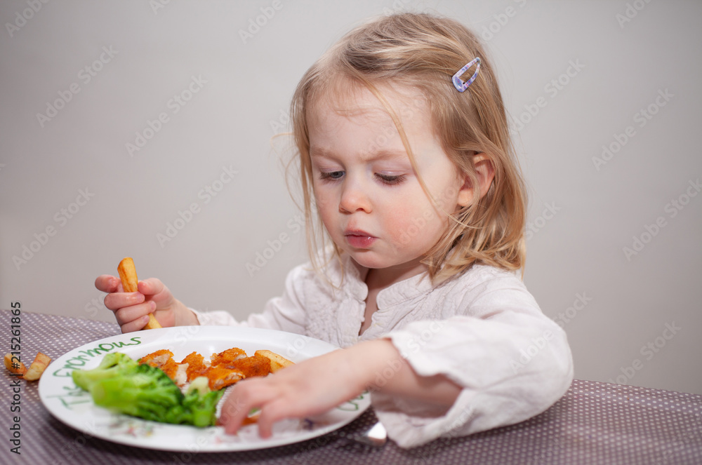 Female toddler eating dinner at the table Female toddler eating dinner at the table