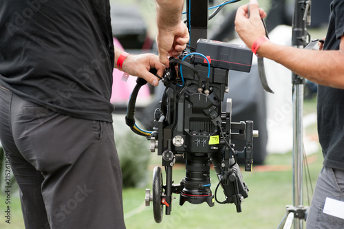 Technical camera operators set professional video camera on a large crane jib arm. 