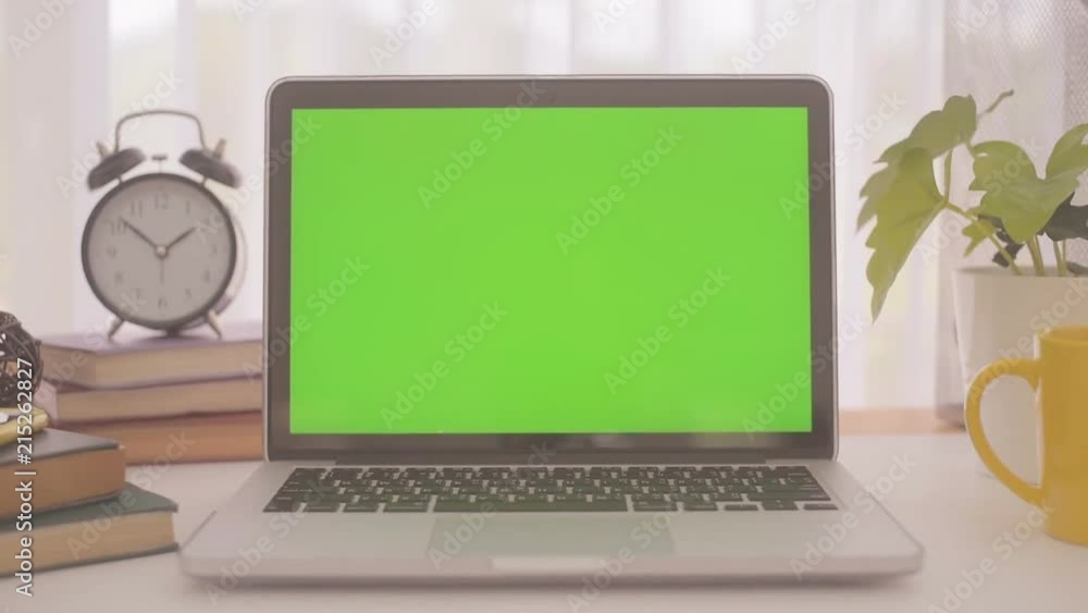 A laptop computer with a key green screen set on work office table. A laptop computer with a key green screen set on work office table.