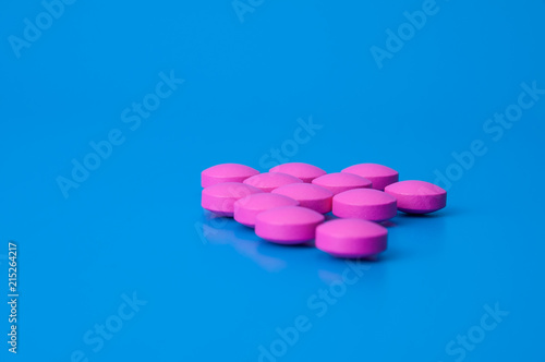 Bright pink pills on a blue background. Location in the middle of the image photo