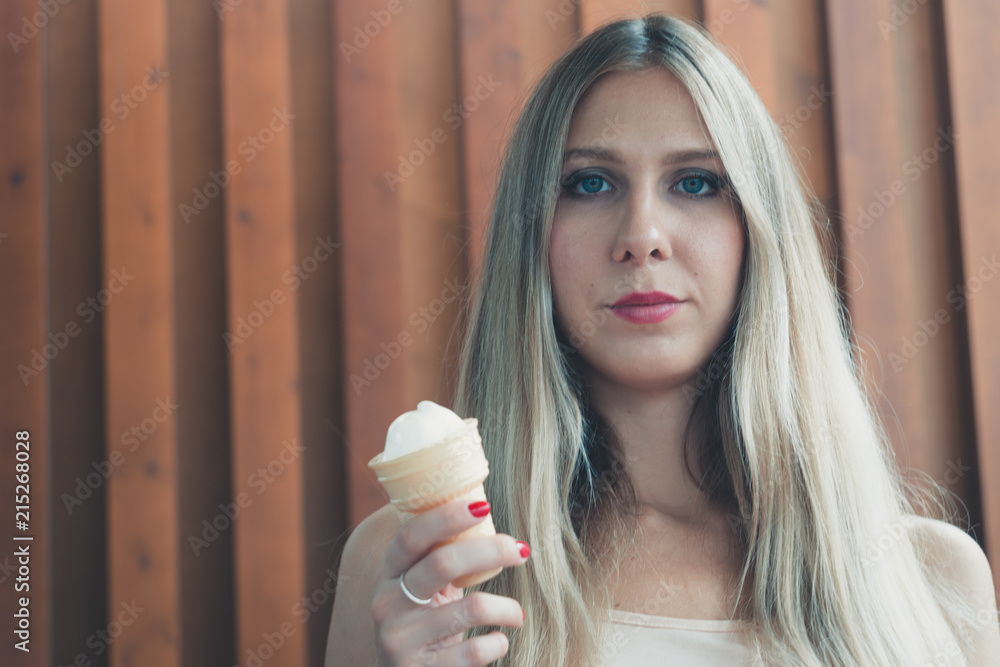 Foto de Pretty young girl licks a horn with ice cream on a hot day