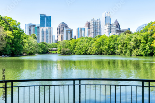 Cityscape, skyline view in Piedmont Park in Atlanta, Georgia green foliage, trees, scenic water, urban city skyscrapers downtown at Lake Clara Meer by railing photo