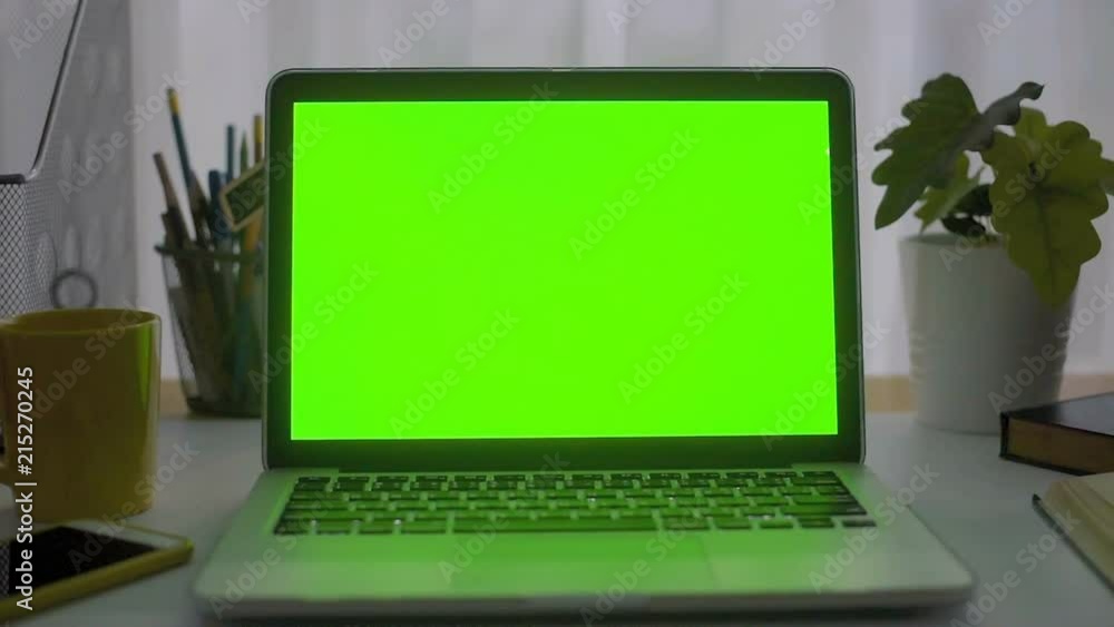 A laptop computer with a key green screen set on work office table. A laptop computer with a key green screen set on work office table.