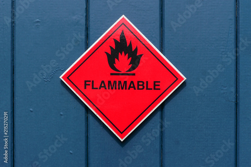 Red diamond shape flammable warning sign on a blue door photo