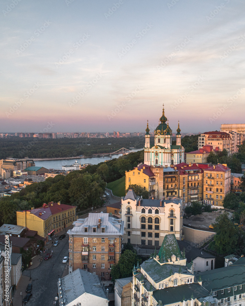 Panorama of the city of Kiev with the domes of St. Andrew's Church in the foreground, the historic district of Podol and the Dnieper River in the background. Aerial view