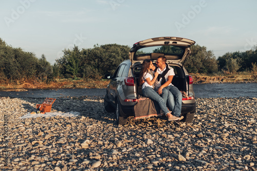 Happy Couple on Roadtrip into the Sunset in SUV Car