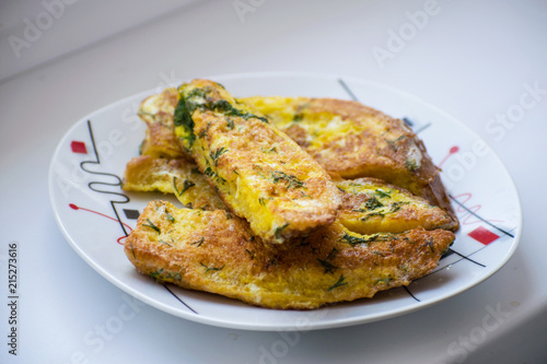 Fried bread in an egg with dill. Fried bread on a plate. Breakfast - bread and eggs.