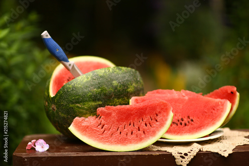 cut ripe big water melon still life with knife on green garden background close up photo photo