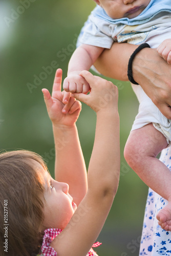 Sister holding gently her newborn borther's tiny hand photo