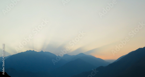 sun rises behind a mountain