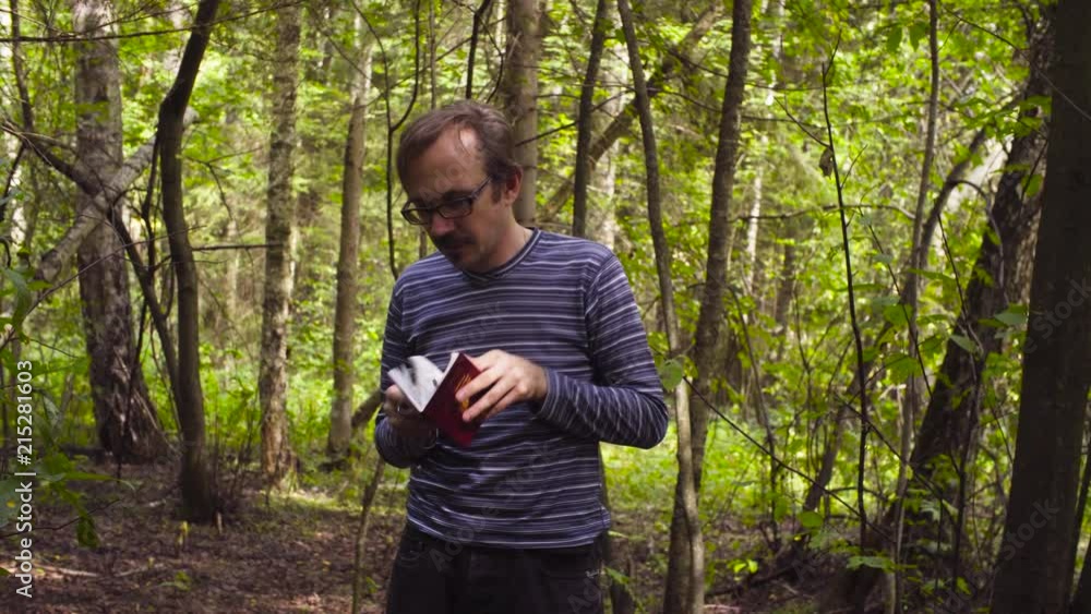 Man and woman scientists environmentalists in the forest. Man looking in a diary, then they walking Man and woman scientists environmentalists in the forest. Man looking in a diary, then they walking