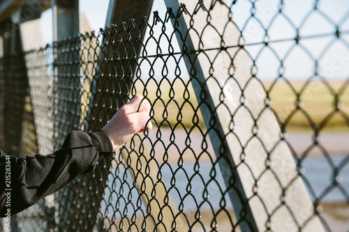 Hand holding onto a wire fence