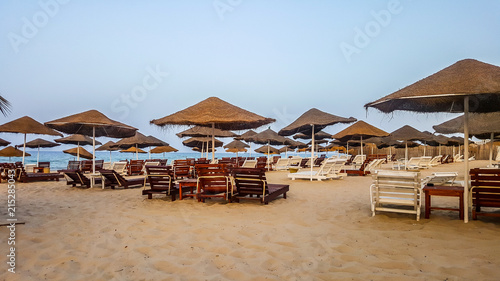 Beach with straw umbrellas in the evening. 