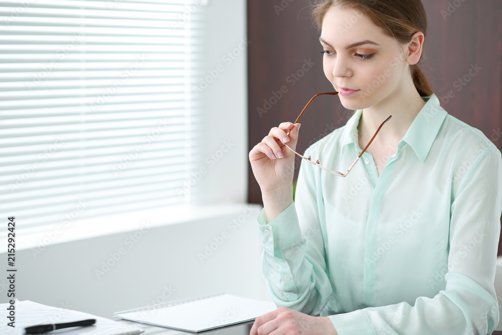 Business woman or secretary sitting at the desk in the office. Green toned image Business woman or secretary sitting at the desk in the office. Green toned image